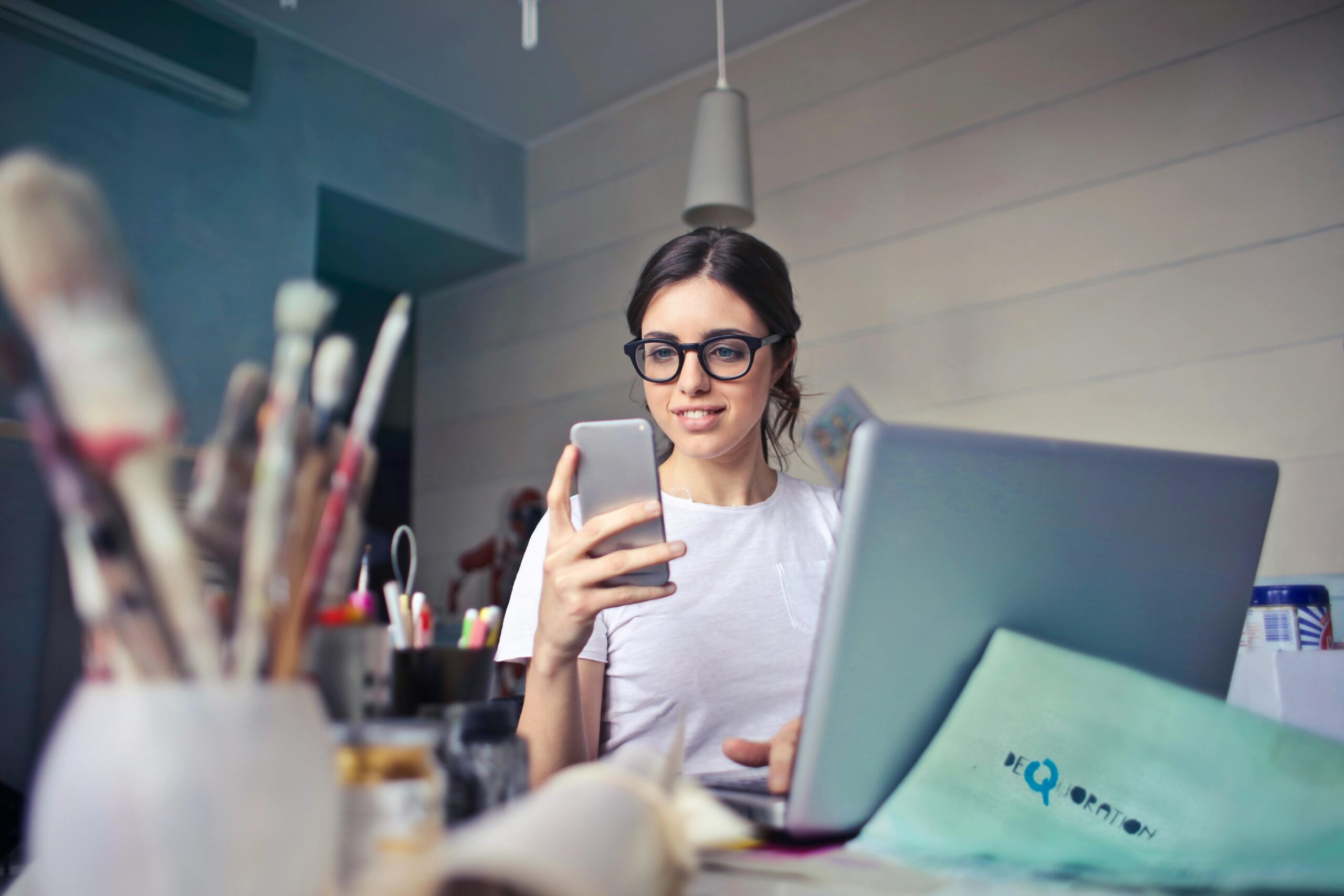Frau Im Weißen T Shirt, Das Smartphone Vor Laptop Hält