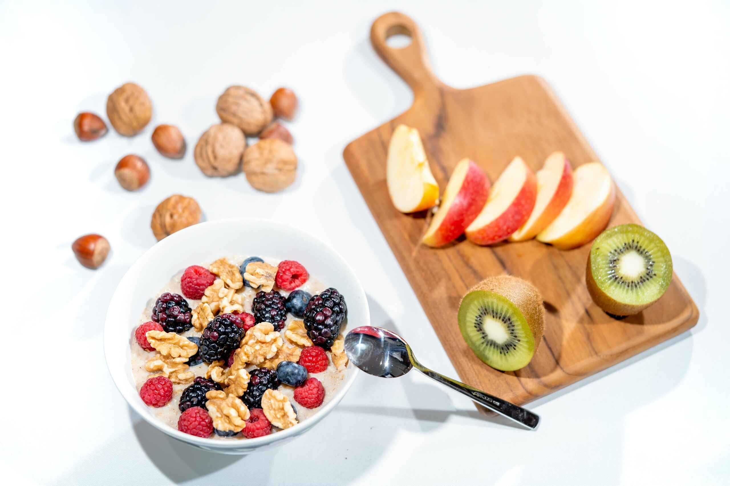 Eine nahrhafte Frühstücksschüssel mit frischen Beeren und Walnüssen, serviert mit geschnittenem Obst und Kiwi.