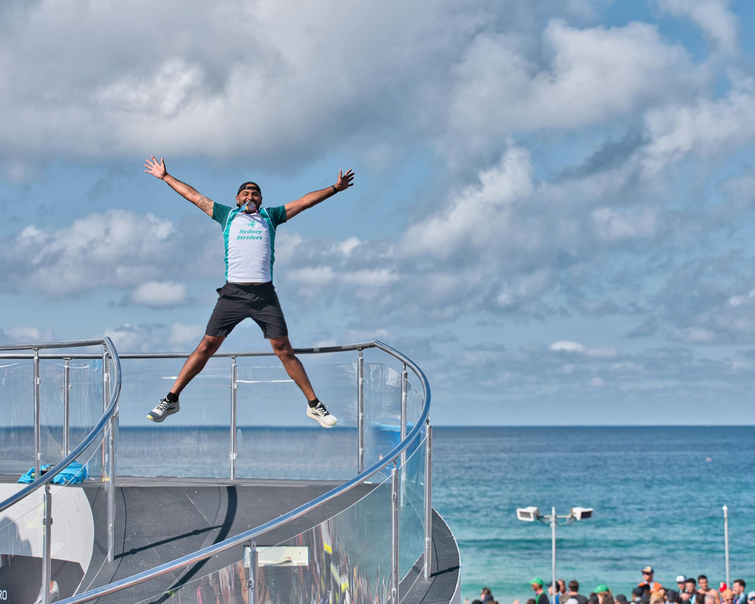 Mann springt vor Aufregung bei einem Marathon am Strand in Sydney, Australien.
