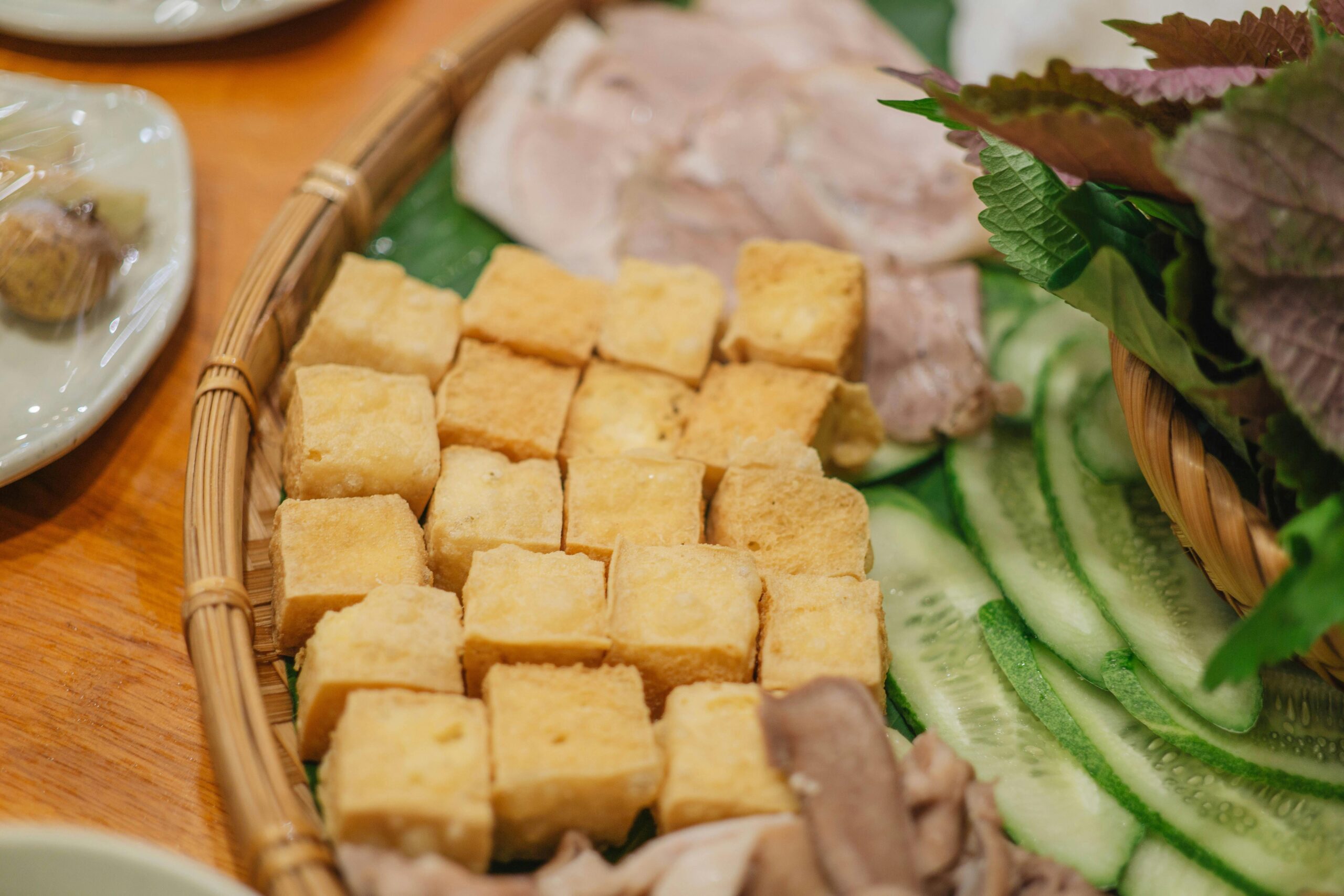 Köstliche vietnamesische Platte mit Tofu, Gurke und Kräutern auf einem Holztisch.