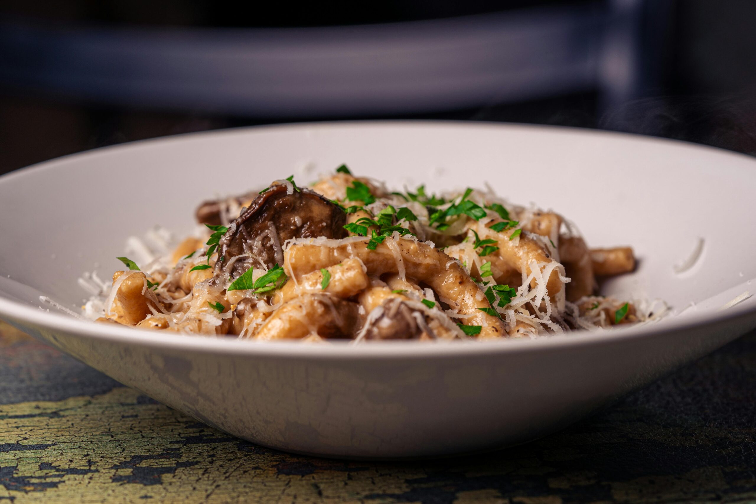 Appetitliche cremige Pasta mit Pilzen, garniert mit frischer Petersilie und Parmesan.