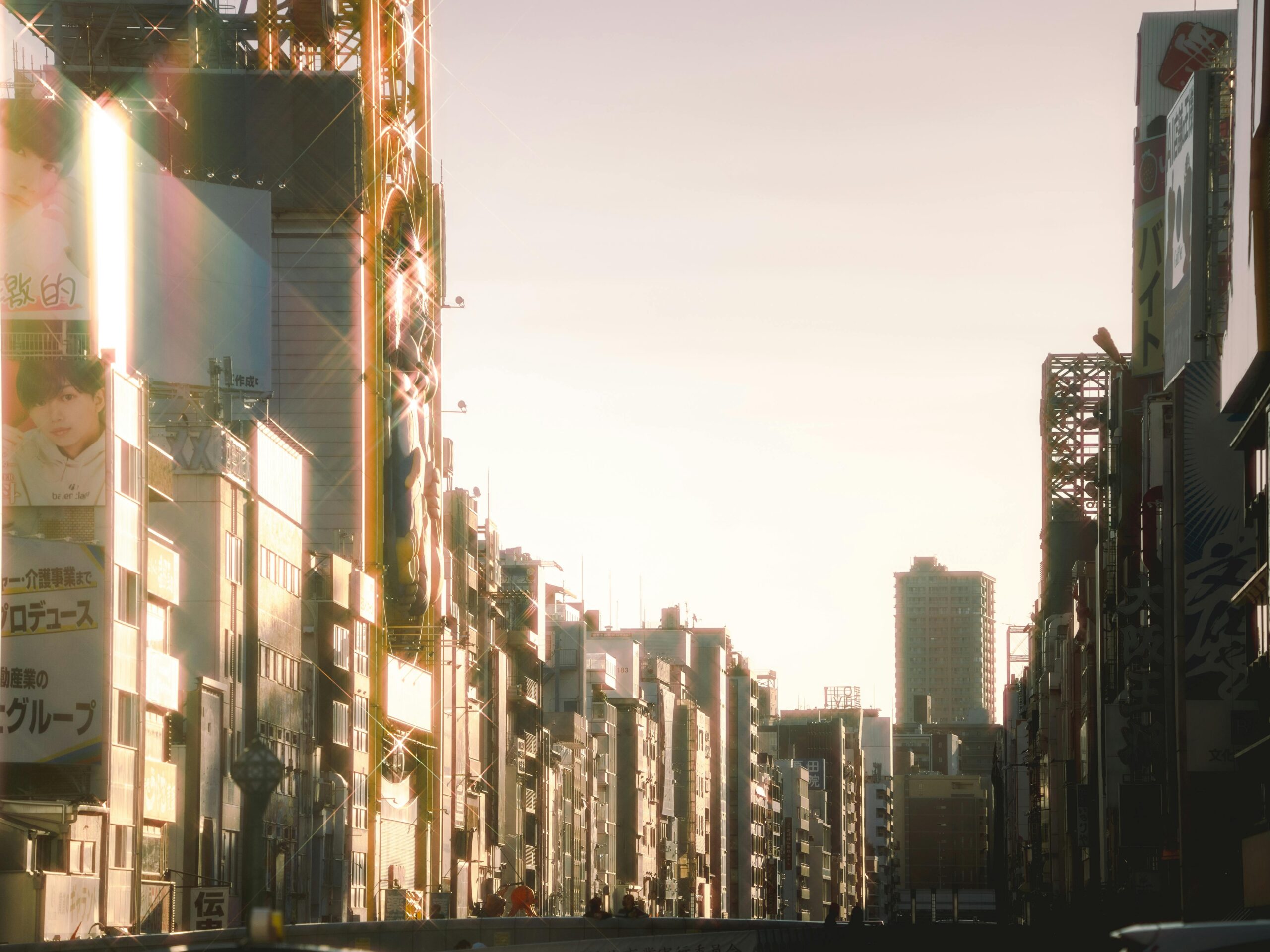 Blick bei Sonnenuntergang auf eine belebte Stadtstraße mit Wolkenkratzern und Werbetafeln in Japan.