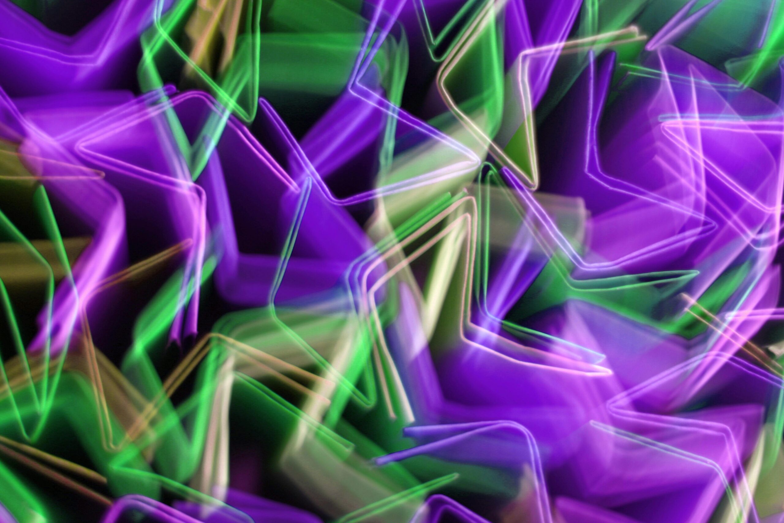 Dynamisches abstraktes Bild mit leuchtend violetten und grünen Lichtspuren in Bewegung.