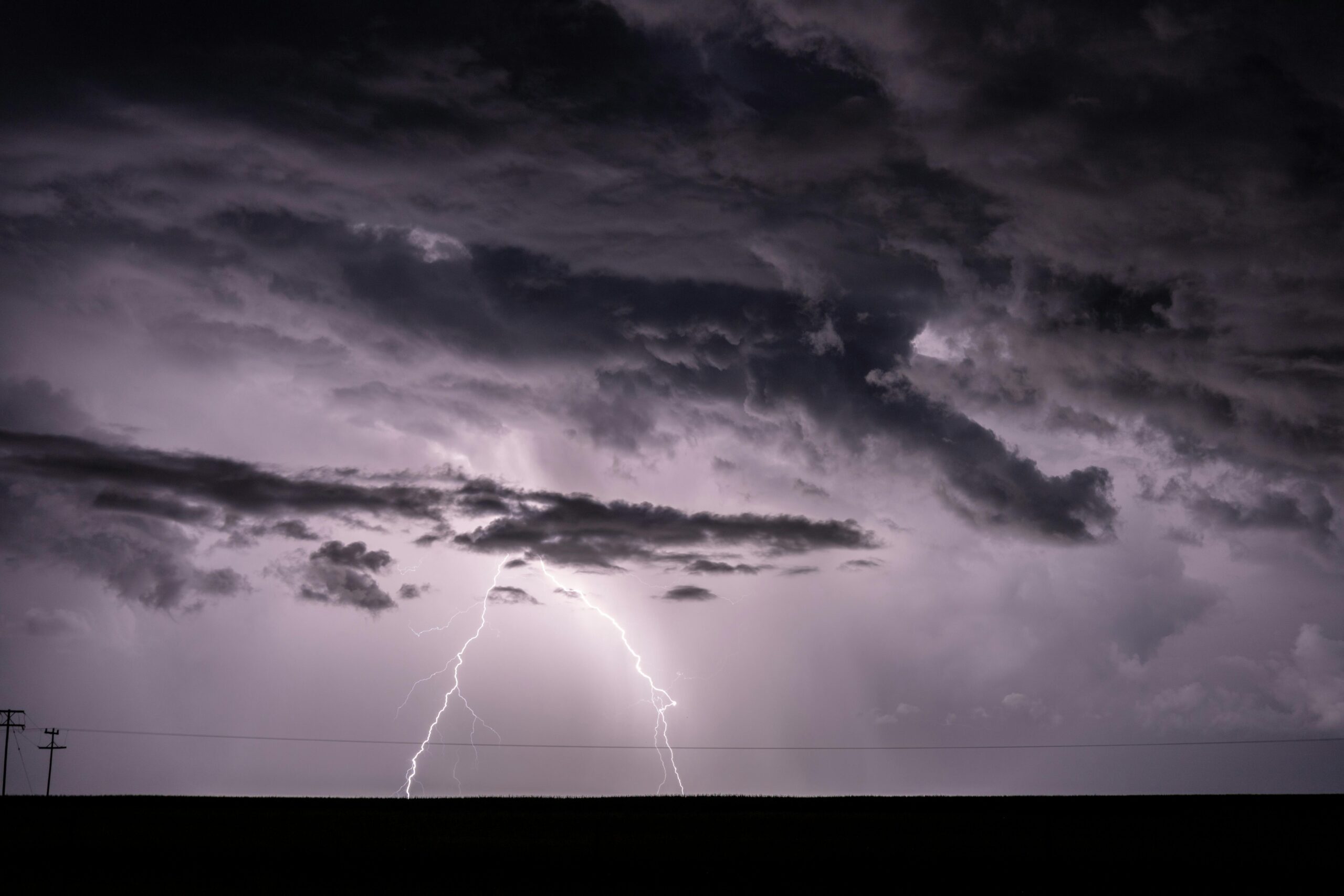 Bei einem nächtlichen Gewitter erhellt ein kräftiger Blitz dunkle Wolken.