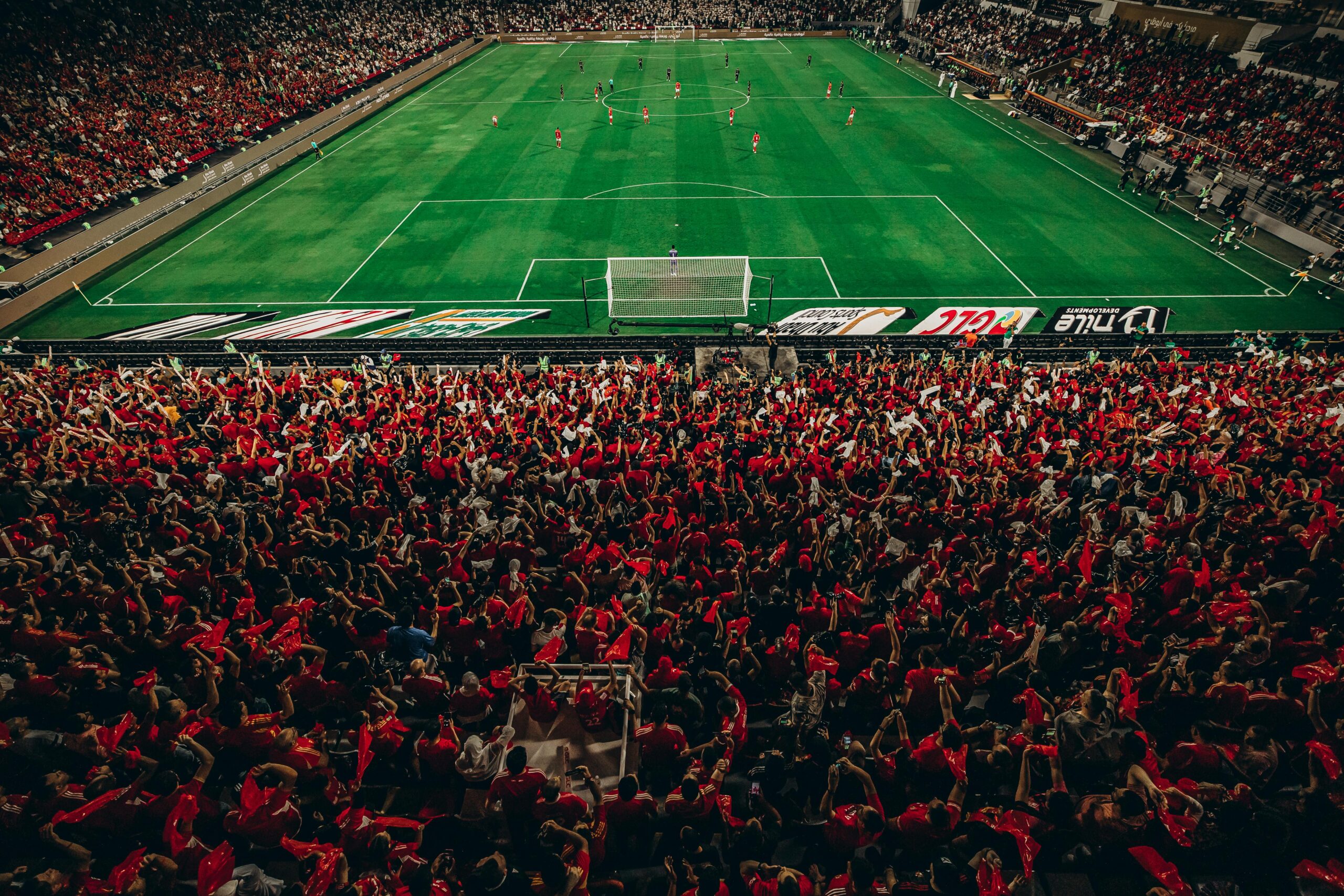 Luftaufnahme eines lebhaften Fußballspiels mit begeisterten Fans in einem voll besetzten Stadion.
