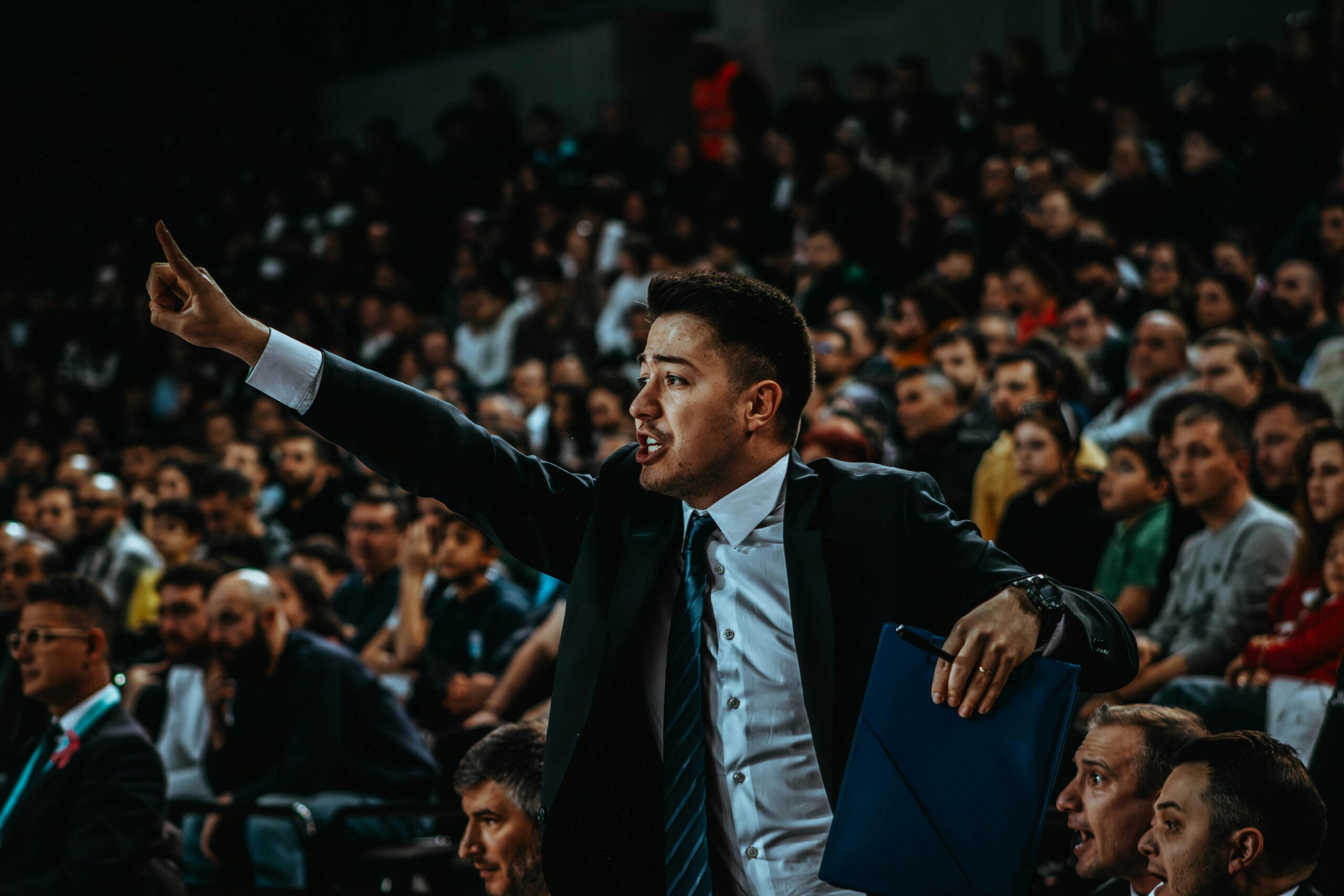 Motivierter Trainer leitet während eines spannenden Basketballspiels in einer überfüllten Arena.