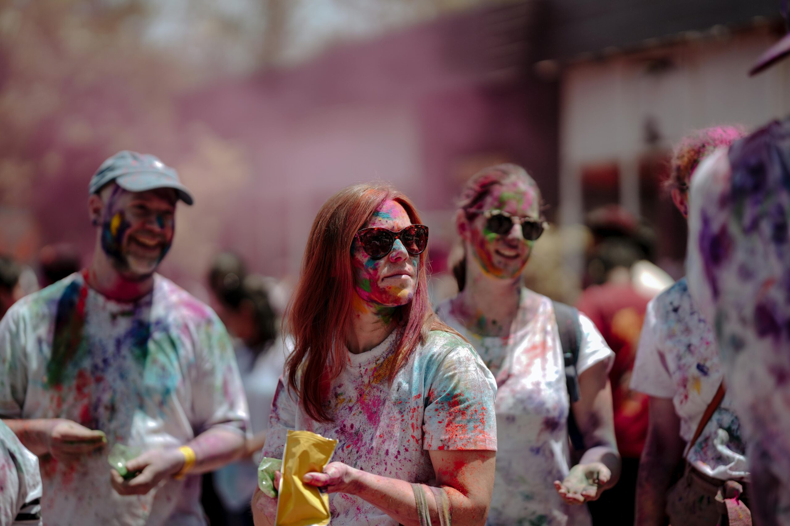 Eine lebhafte Holi-Feier im Freien, bei der die Menschen mit buntem Pulver bedeckt sind.