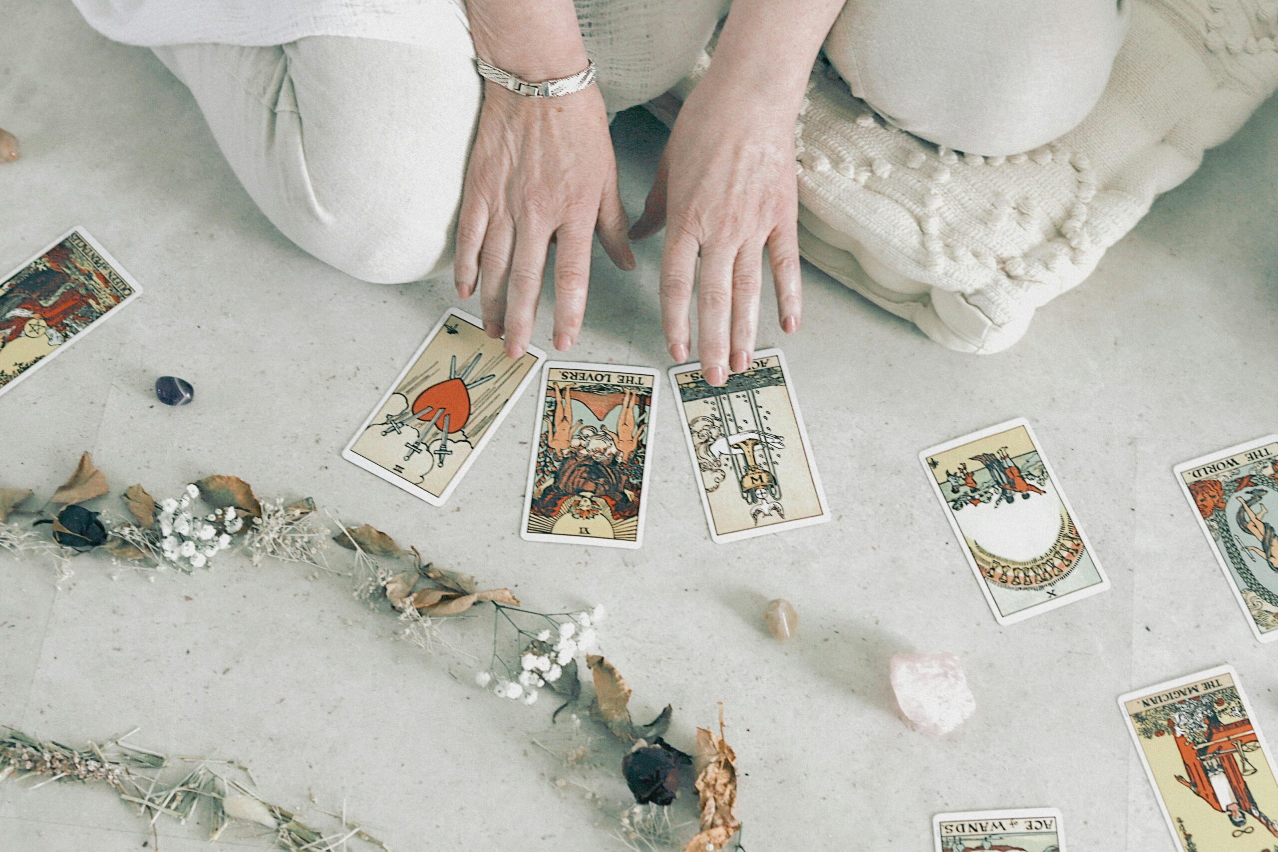 HÃ¤nde arrangieren Tarotkarten mit Kristallen und getrockneten Blumen auf einer ruhigen OberflÃ¤che.