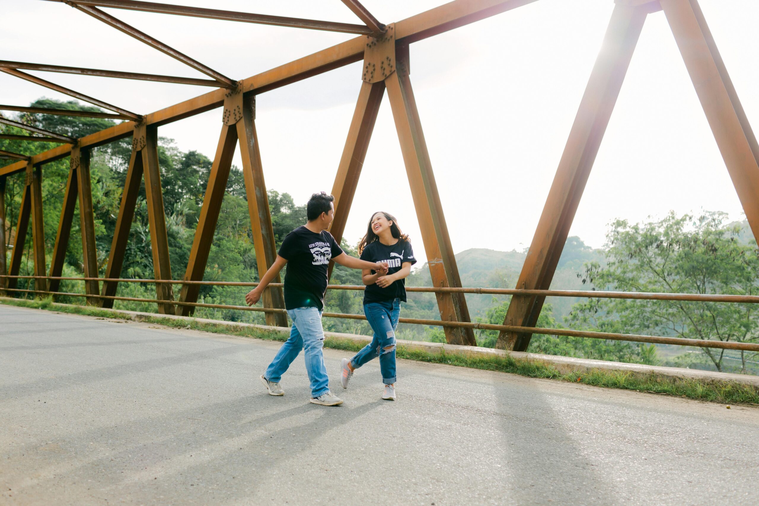FrÃ¶hliches Paar tanzt auf einer EisenbrÃ¼cke in Davao City inmitten einer malerischen Umgebung.