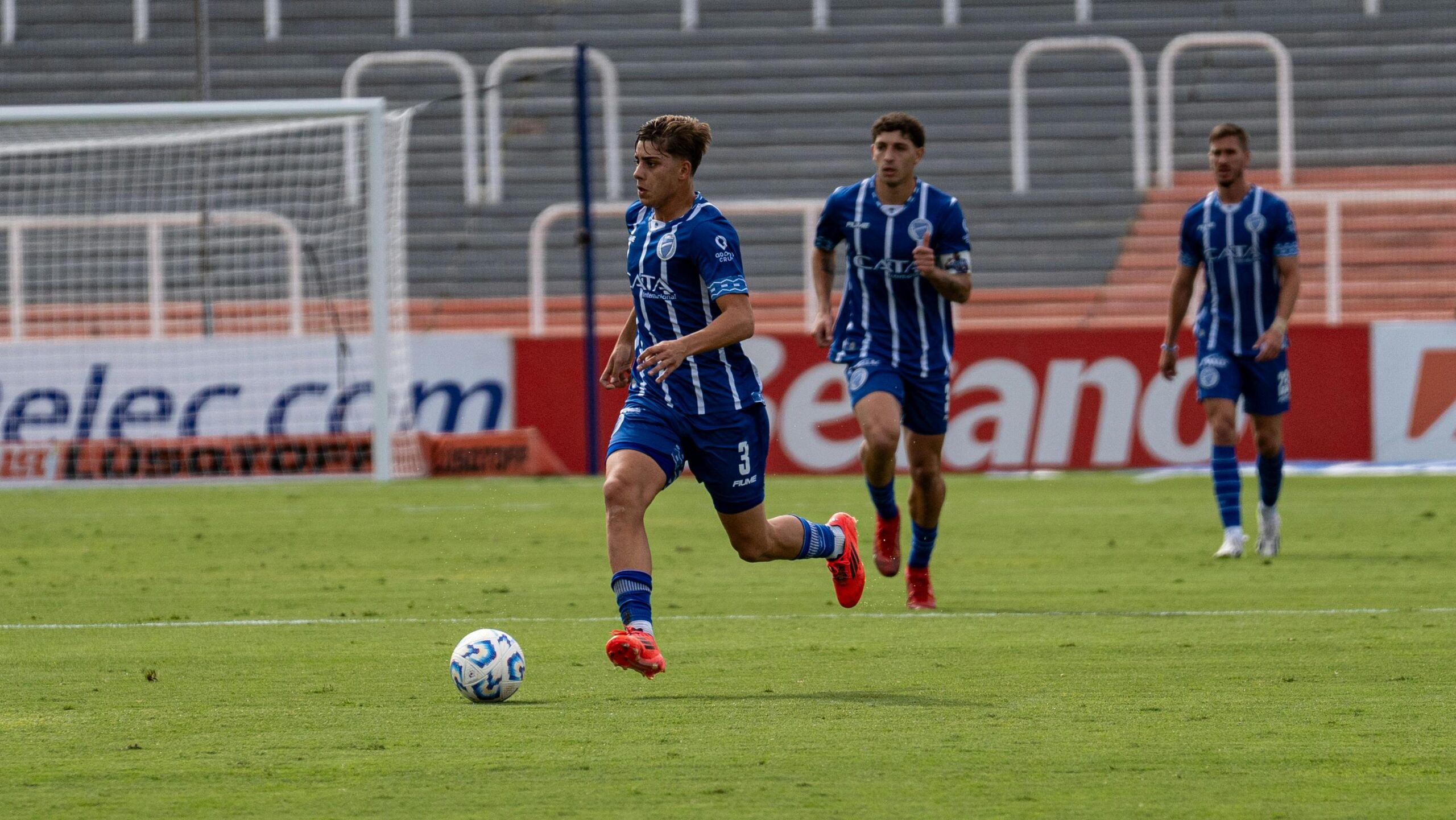 Spannender Moment während eines Fußballspiels, wenn Spieler in blauen Uniformen auf dem Spielfeld die Kontrolle über den Ball übernehmen.