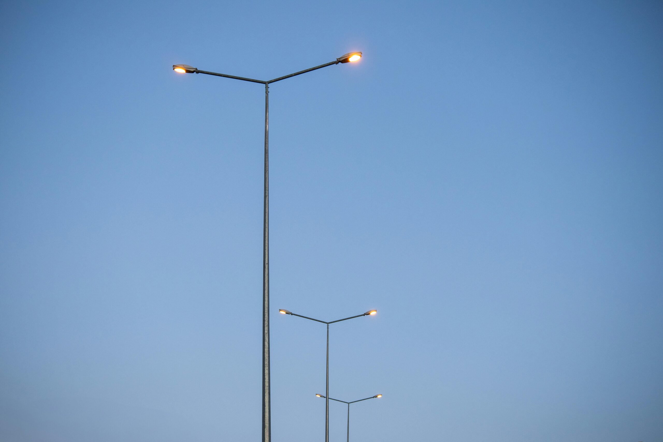 Symmetrische Reihe von StraÃŸenlaternen, die sich tagsÃ¼ber in Palu, ElazÄ±ÄŸ, TÃ¼rkei, in den klaren blauen Himmel erstrecken.